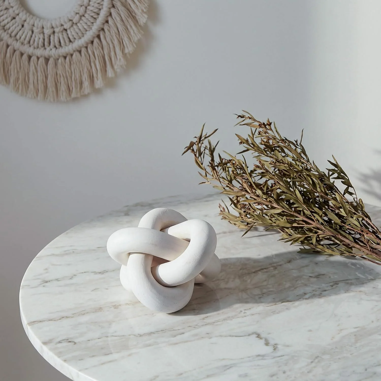 White wood knot sculpture, White: knot beside a decorative vessel